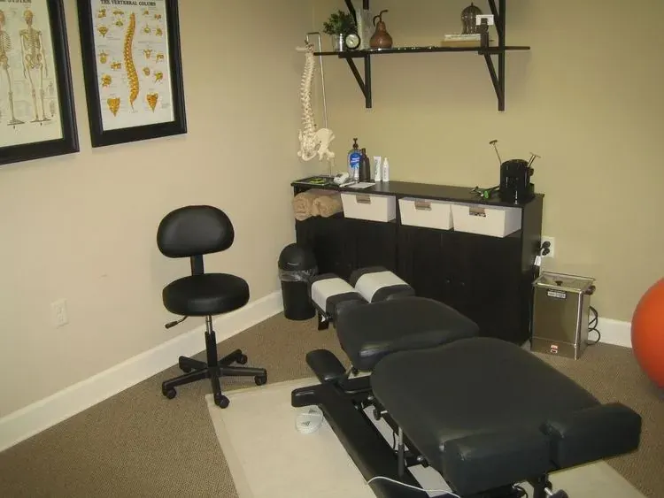A treatment room with an adjusting table and spine charts at Fortier Chiropractic
